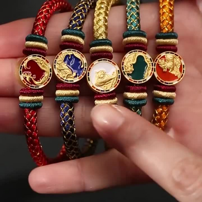 Five colorful bracelets with zodiac symbols held in a hand against a dark background