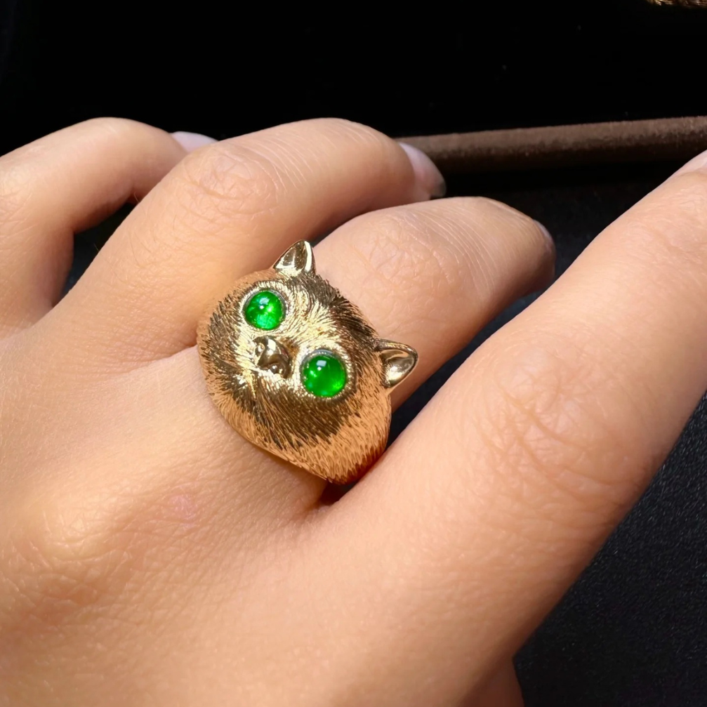 vintage-inspired 18k carved gold prosperity cat ring with emerald green fluorescence