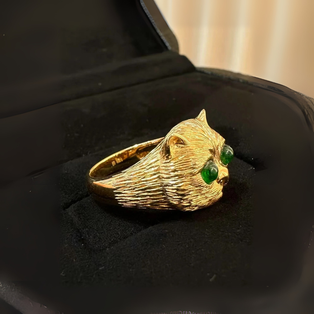 vintage-inspired 18k carved gold prosperity cat ring with emerald green fluorescence