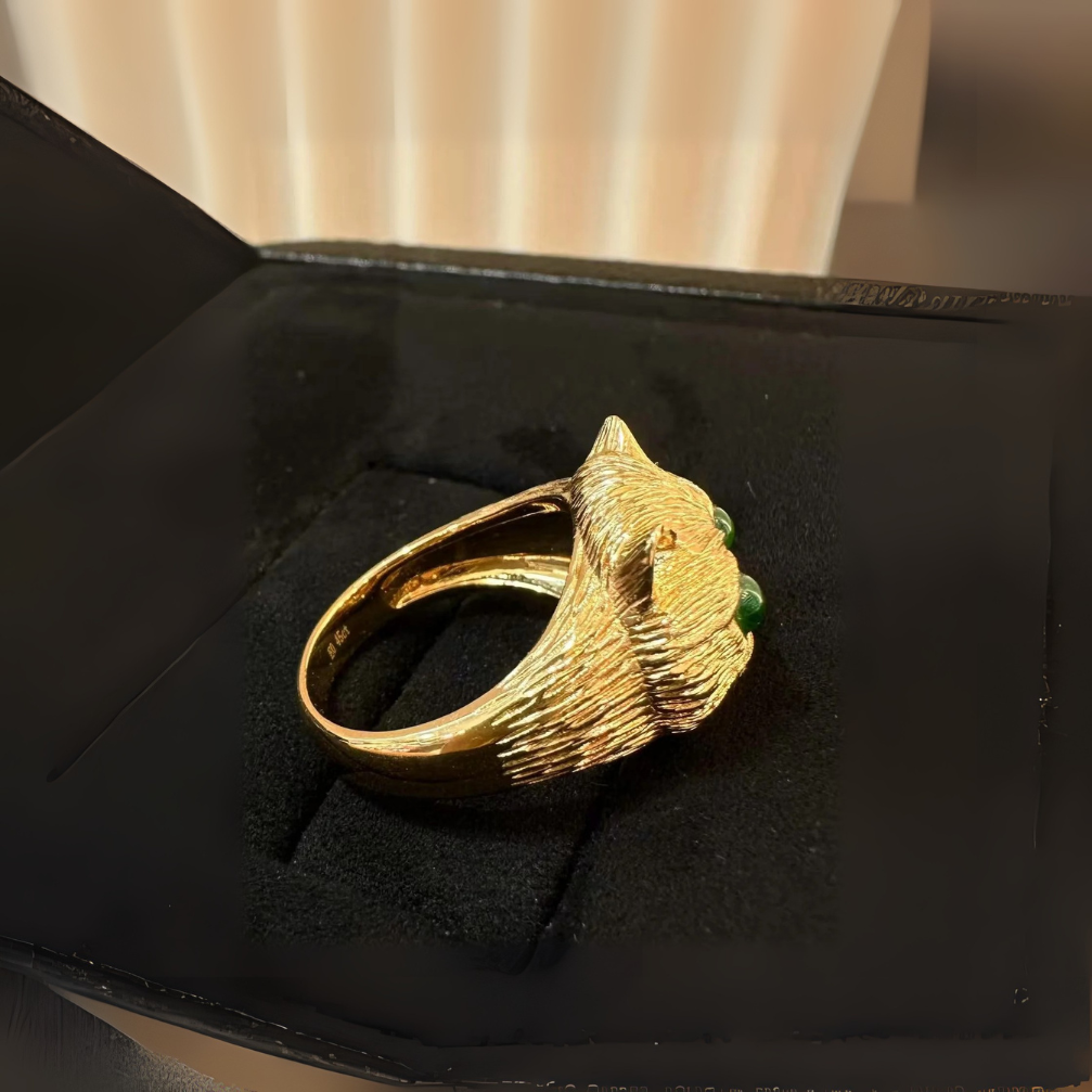 vintage-inspired 18k carved gold prosperity cat ring with emerald green fluorescence